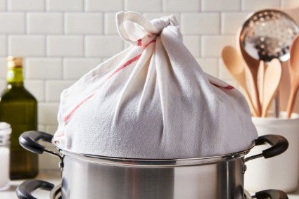 Metal steamer with kitchen towel tied around lid